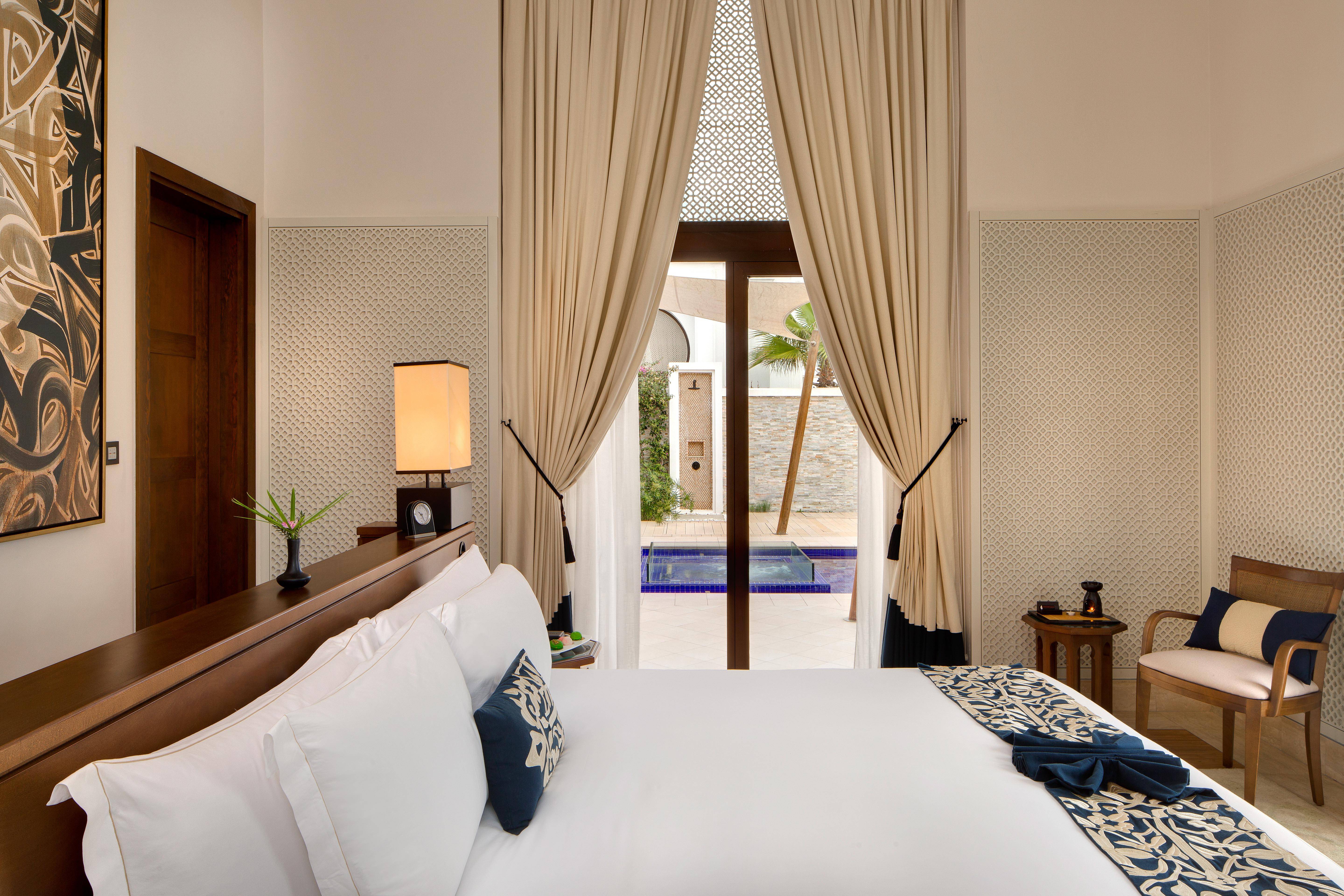 Bed overlooks pool through curtains in Banyan Tree Tamouda Bay Harmony Seaview Pool Villa.
